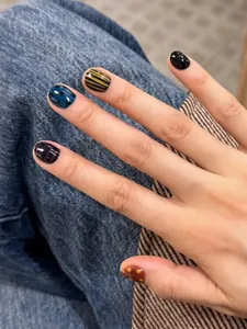 Detailed view of short press-on nails featuring irregular grids and colorful polka dots