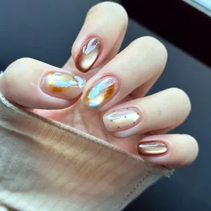 Uñas postizas de ojo de gato ámbar con pan de oro y purpurina azul para un look elegante