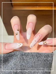 Detailed close-up of long almond pink gradient press-on nails with cat paw and heart patterns