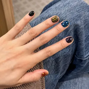 Artistic press-on nails with plaid patterns and dots on a denim fabric background