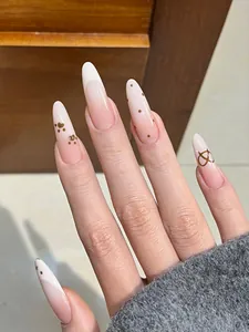 Detailed view of long almond press-on nails with nude pink gradient and gold accents