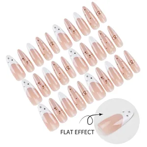 Long almond press-on nails with nude pink gradient, black dots, and heart patterns