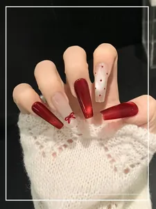 Detail of red cat-eye gradient press-on nails with 3D bow accent on lace sleeve background
