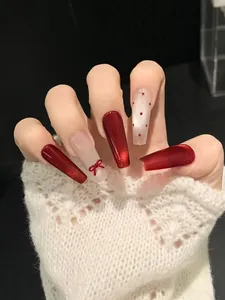 Detailed view of red cat eye press-on nails with 3D bow and polka dot accents