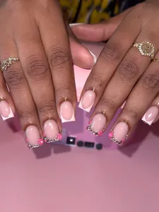Dettaglio unghie finte rosa stile francese con petali 3D e strass argentati