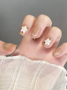 Detalle de uñas cat-eye rosa nude con flores 3D blancas y un acabado brillante elegante
