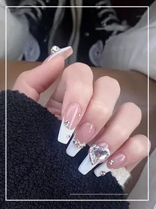 Detail of French white tip press-on nails with sparkling rhinestones and a heart gemstone