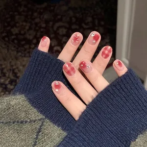 Kurze rote Press-On-Nägel im Blush-Karo-Design mit Strasssteinen und Herz-Anhängern