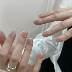 Detail von kurzen Ballet-Katzenaugen-Nägeln mit rosa Verlauf, Perlen und Strass