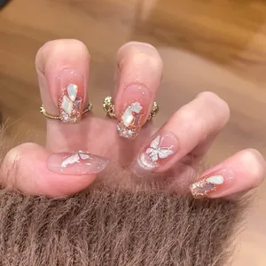 Dettaglio di unghie finte rosa nude con farfalla 3D, strass ed effetto cat-eye lucido
