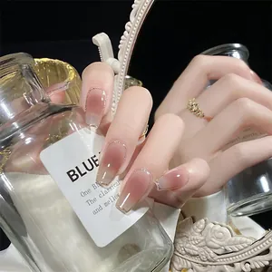 Macro detail of nude pink gradient press-on nails with elegant gold glitter tips