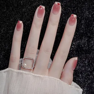 Detail of pink gradient press-on nails with heart patterns and a pearl ring over black lace