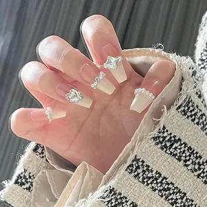 Detail of luxury press-on nails with cream nude base and exquisite pearl heart rhinestones