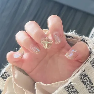 Detail of 3D gold butterfly charm on shimmering aurora press-on nails with glitter finish