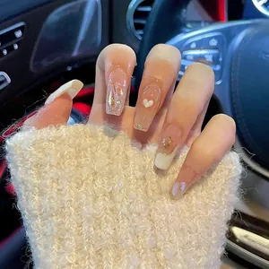 Detail of long ballerina press-on nails with pink base, white French tips and 3D heart