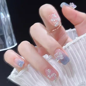 Detail of short blue gradient press-on nails with butterfly and pearl accents