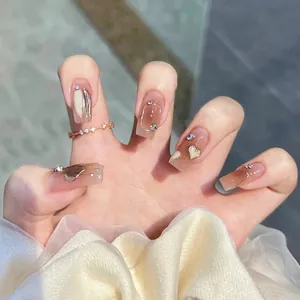 Detail of coffee gradient press-on nails with 3D heart charms and sparkling rhinestones