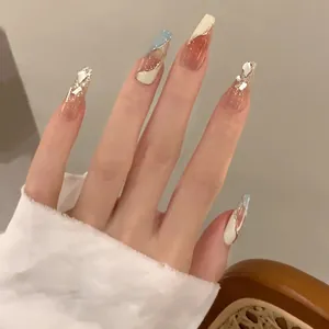 Détail de faux ongles cercueil or champagne aurora avec strass 3D et perles élégantes