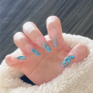 Détail de faux ongles cercueil avec dégradé pailleté argenté et strass bleus brillants