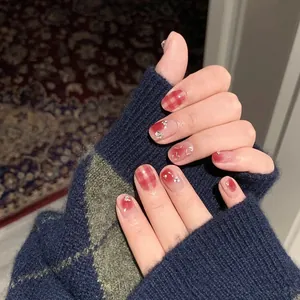 Short round press-on nails with red checkerboard and pink blush design with silver heart