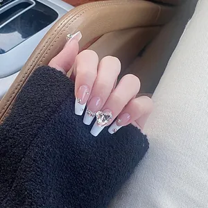 Macro view of coffin shaped french nails with large heart crystal and small rhinestones