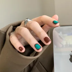 Short square press-on nails in deep brown and peacock green with a refined finish