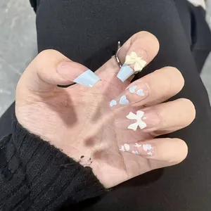 Detail of long coffin press-on nails with 3D blue bows and heart patterns on hands