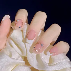Detail of pink French press-on nails with golden metal lines and small rhinestones