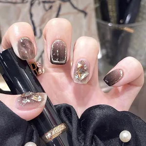 Detail of coffee brown marble press-on nails with gold foil and luxury oversized rhinestones