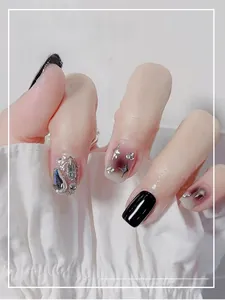 Close-up of black and glitter aurora press-on nails with silver stars and 3D rhinestones