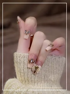 Macro shot of press-on nails with pink gradient, rhinestones and pearl bow accents