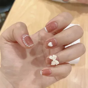 Close-up of pink jelly nails with white French tips, pearls, and 3D bow decorations