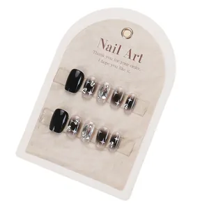 Short black press-on nails with silver glitter, star patterns, and rhinestones