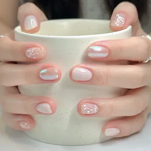 Pink press-on nails with bow and rhinestone details on a short round shape
