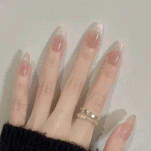 Glossy almond shaped nude pink gradient press-on nails on elegant manicured hand