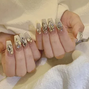 Close-up of handmade luxury coffin nails with nude gradient, diamonds and white pearls