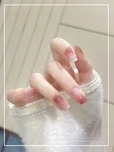 Detail of pink gradient press-on nails with a glossy finish on a hand model