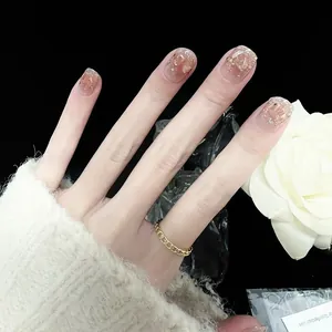 Detail of short square press-on nails with pink gradient, gold foil, and glitter accents