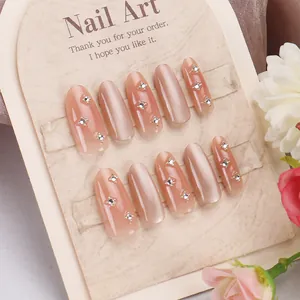 Nahaufnahme der nude-rosa Katzenaugen-Drucknägel mit Kristallblumen und Stern-Strasssteinen