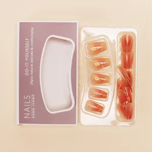 Ballerina style amber red gradient press-on nails with gold swirl design and packaging