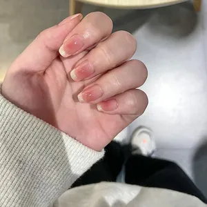 Close-up of short square french ombre press-on nails with pink gradient and glitter tips