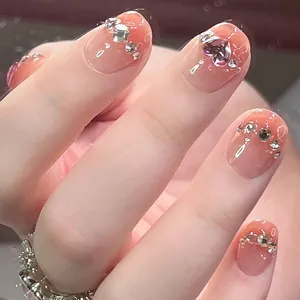 Macro shot of peach gradient press-on nails with heart gemstone and sparkling rhinestones