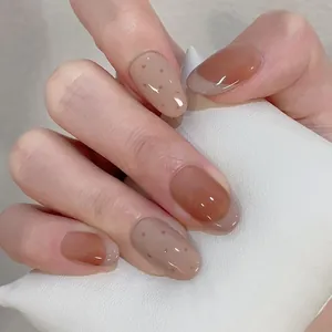 Short oval French press-on nails in amber and khaki colors with brown polka dots design