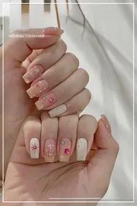Detail of pink and cream wearable nails featuring star, moon, and heart designs with rhinestones