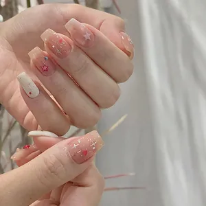 Close-up of nude pink jelly gradient press-on nails with stars and rhinestone heart details