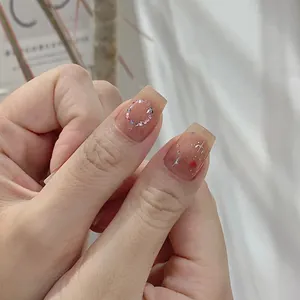 Square press-on nails with nude tint, rhinestone circles, and silver starburst details