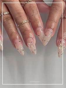 Detail of nude press-on nails with silver star patterns and 3D bow accents