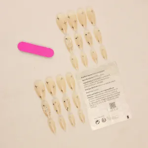 Translucent nude press-on nails with brown stars, silver bows and rhinestones