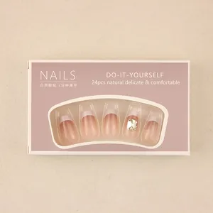 Macro shot of French pink press-on nails with white tips and a large crystal accent