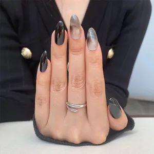 Detalle de uñas almendradas con acabado negro brillante y patrones de mármol en la mano del modelo